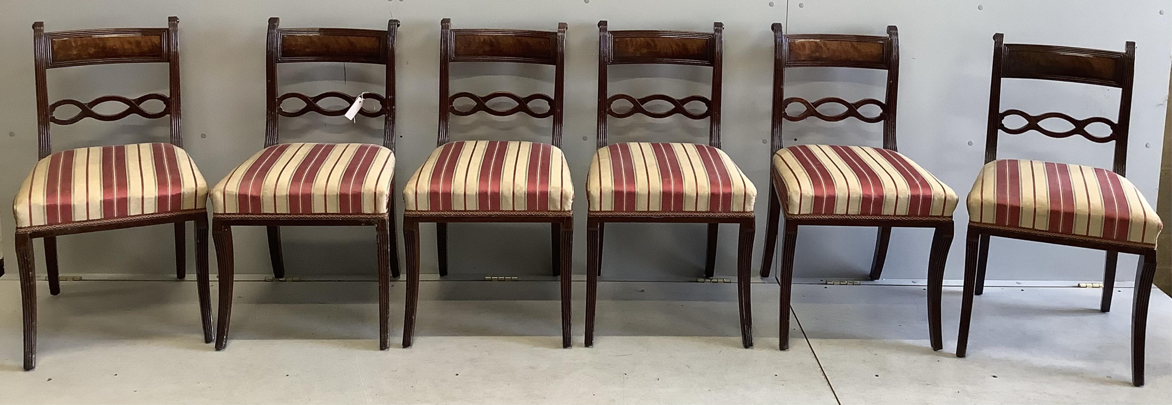 A George III mahogany oval pedestal dining table with brass claw feet, width 152cm, depth 105cm, height 71cm, together with a set of six Regency mahogany sabre leg dining chairs. Condition - fair to good